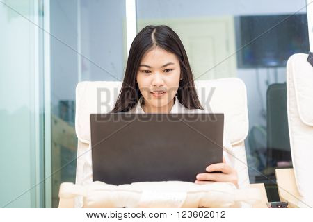 Young Asian Woman Using Laptop On Sofa In Condominium