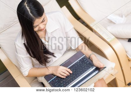 Young Asian Woman Using Laptop On Sofa In Condominium