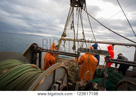 Fishermen in waterproof suits on the deck of the fishing seiner. Morning time.