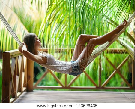 Young beautiful woman relaxing in hammock in a tropical resort