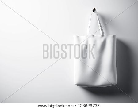 Photo white cotton textile bag hanging right side. Empty concrete wall  background. Highly detailed texture.