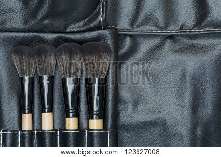 top view of makeup brushes on black leatherette background