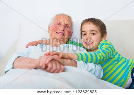 Grandmother with her grandson in pajamas getting ready to sleep.