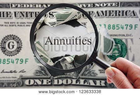 Hand holding a magnifying glass over torn dollar bill with Annuities text
