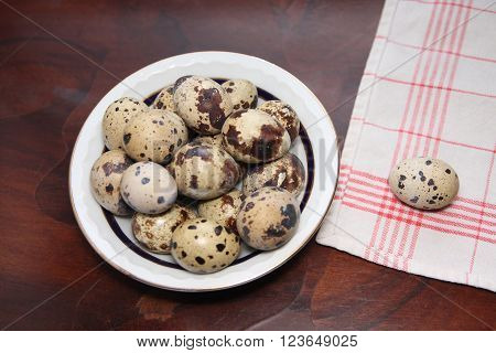 Partridge eggs in a bowl on a wooden table