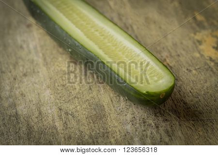 Cucumber sliced lengthwise with seeds on grungy wooden table