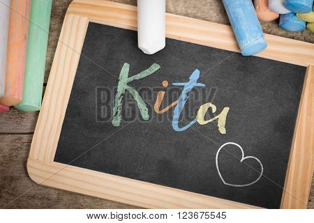 Slate with german word Kita, which means Kindergarten, colorful crayon on wooden Table, flat lay