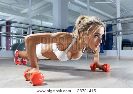 Sportive woman push-ups on the floor at the gym