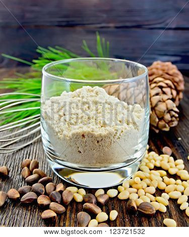Flour cedar in a glass, cedar nuts and two cones, cedar branch against the backdrop of wooden planks