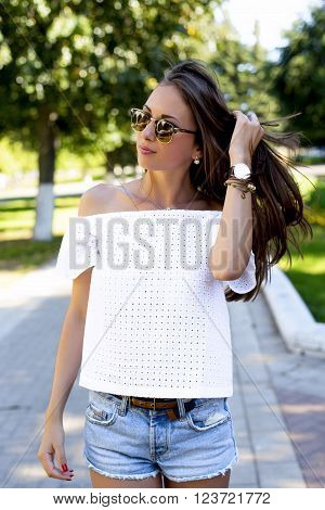 Beautiful girl walking in the park, in a white jacket, sunglasses, shorts, fashion style urban life, a bright sunny summer day. Outdoors brunette woman straightens her hair.
** Note: Soft Focus at 100%, best at smaller sizes