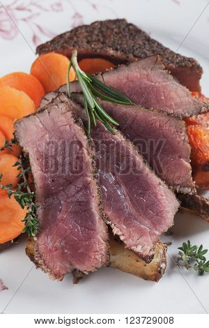Medium rare beef pepper steak with carrot, thyme and rosemary