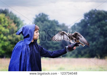 handsome young man in a raincoat with a falcon in his hand