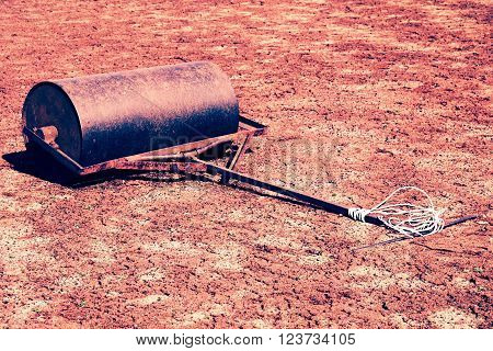 Old Rusty Iron Barrel For Maintenance Of Neglect Tennis Court. Old Dry Red Crushed Bricks Surface On