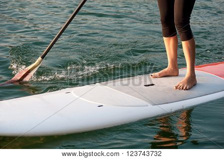 front view of a young woman paddleboarding in sports clothing SUP