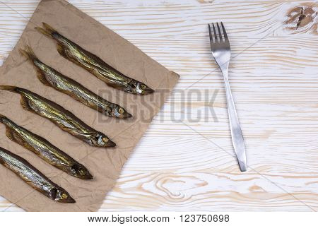 Smoked  capelin on light vintage wooden background, top view