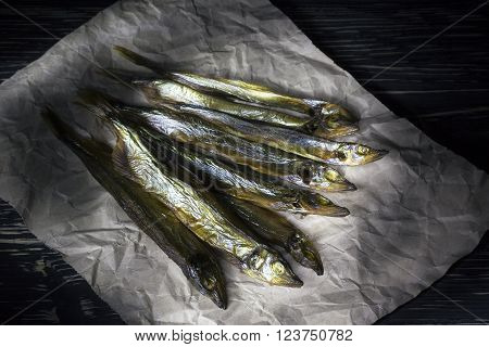 Smoked salted capelin on vintage wooden background, top view