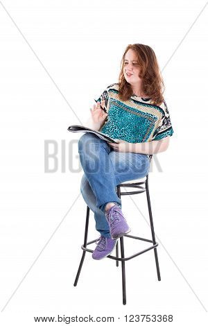 Beautiful smiling redhead plus size wreckled model with folder and ballpoint pen sitting on the bar chair. Isolated on a white background.