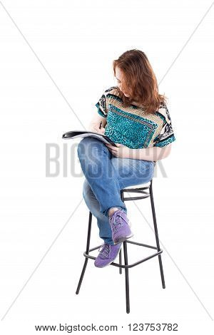 Beautiful smiling redhead plus size wreckled model with folder and ballpoint pen sitting on the bar chair. Isolated on a white background.
