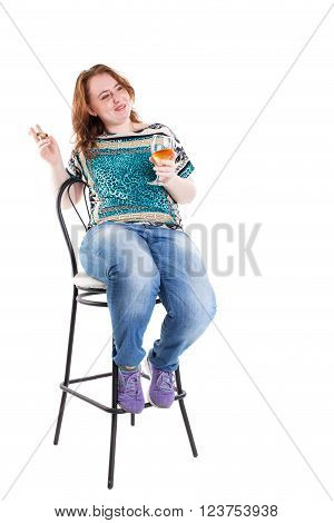 Smiling redhead plus size wreckled model sitting on the bar chair with glass of whiskey and cigar. Studio shot. Isolated on a white background.
