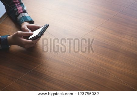 Woman sitting at table and typing a text message on her mobile phone