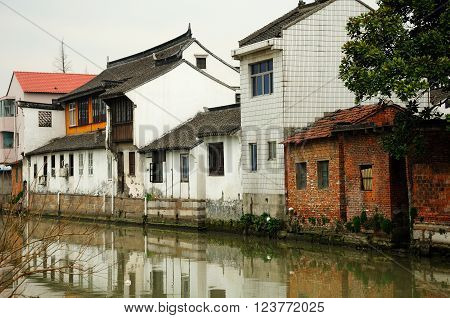 Old buildings in traditional Asian architecture lining a dirty water canal in Sijing Ancient town located in Songjiang district of Shanghai China.