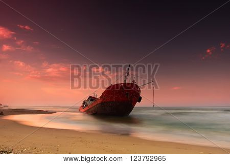 Ship after wreck on the coast colorful sunset