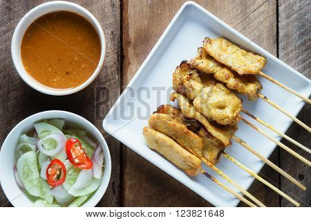 Pork satayGrilled pork served with peanut sauce or sweet and sour sauce with woodbackground