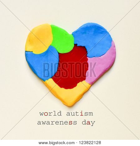 the text world autism awareness day and a heart made from modelling clay of different colors on an off-white background