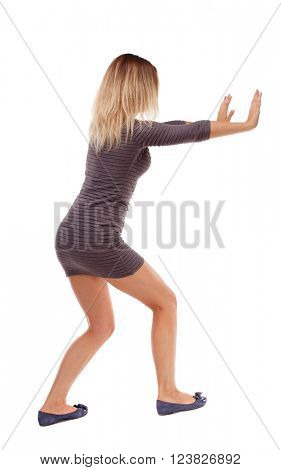 back view of woman pushes wall. Isolated over white background. Rear view people collection. backside view of person. The girl in the brown dress pushes the obstacle in front of him.