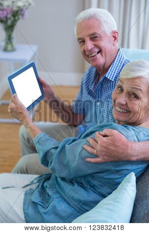 Portrait of happy senior couple holding digital tablet at home