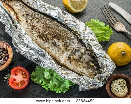 Grilled sea bass fish on the gray table.