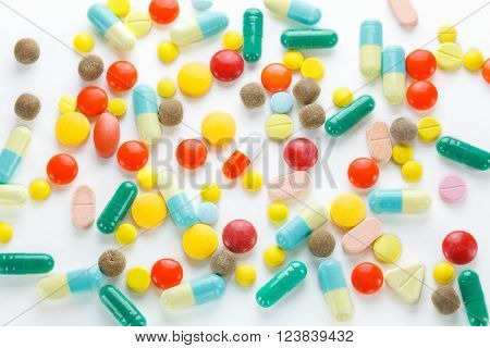 Colorful many tablets pills and pill capsules on white background.