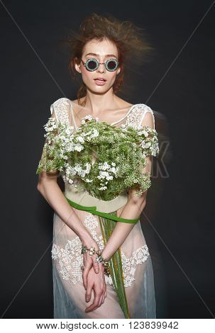 vogue fashion model woman with professional make up and hairstyle in sunglasses with flowers bouqet on dark background