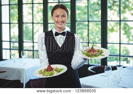 Smiling waitress holding plates in a restaurant