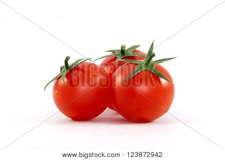 Three fresh ripe cherry tomatoes with a few water drops against white background