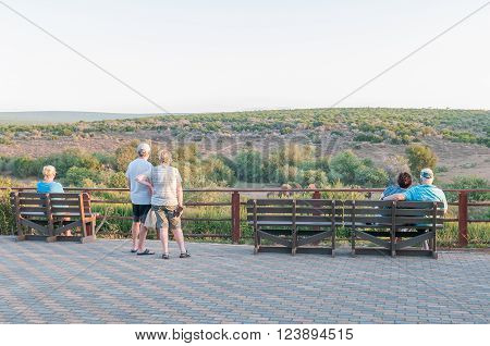 ADDO ELEPHANT NATIONAL PARK SOUTH AFRICA - FEBRUARY 23 2016: Unidentified tourists viewing buffalo in the late afternoon sun at the Nyati waterhole at the main camp