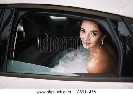 Close-up portrait of elegant bride in a car window. (beautiful bride with freckles)