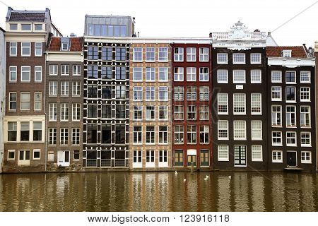 AMSTERDAM; THE NETHERLANDS - AUGUST 16; 2015: Beautiful views of the ancient buildings at the waterside, Damrak canal in Amsterdam. Amsterdam is capital of the Netherlands on August 16; 2015.
