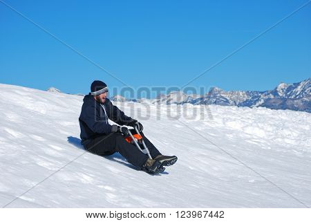 Man in toboggan on a motorcyle sled on a snowhill going down laughing.