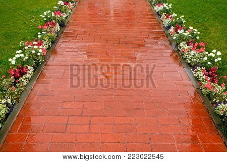 Beautiful pavement of red and brown clinker brick. Walking path decorated with flowers