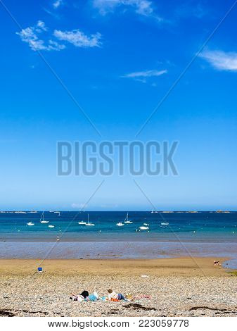 PLOUBAZLANEC, FRANCE - JULY 3, 2010: people on pebble beach Plage de la Baie de Launay on bay Anse de Launay of English Channel in Paimpol region of Cotes-d'Armor department of Brittany in summer day
