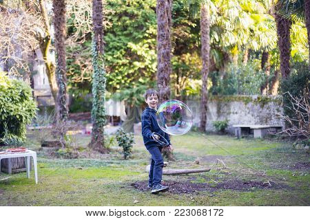 7-year-old Child Outdoors In The Garden In Winter Makes Big Soap Bubbles