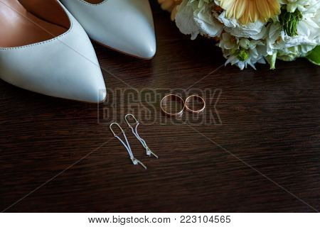 wedding accessories. bridal shoes, bouquet, earrings and rings on wooden background