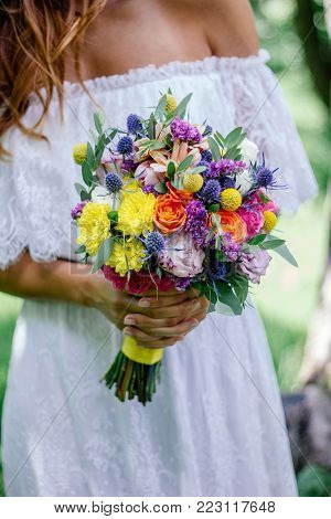 Beautiful Bride Holding Wedding Flower Bouquet In Hands Outdoors