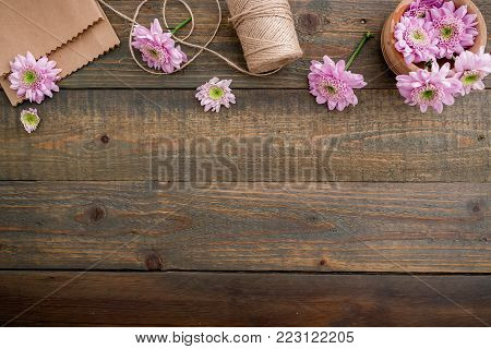 Pink flowers and twine, craft paper on wood background. Flat lay, top view. Woman's background