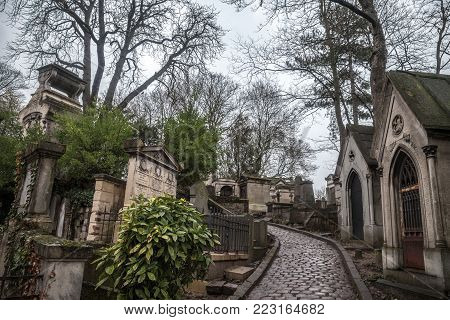 PARIS, FRANCE - DECEMBER 22, 2017: Graves from the 19th century in Pere Lachaise Cemetery in Paris, France, during a cold cloudy winter afternoon. Pere Lachaise Cemetery is the largest cemetery in Paris, hosting major french celebrities