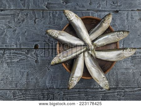 Salted herring in a clay bowl on wooden rustic table. The view from the top. Natural food from the ocean.