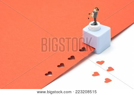 couple Miniature 2 people standing with Heart shaped punching machine Punch red paper Red heart is the promise of love.  as background Valentine concept with copy spaces for your text or design.