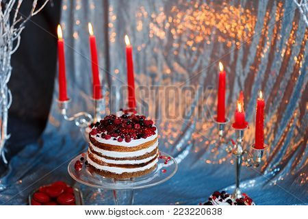 Sweet bar with muffins cakes, sweets, fruits and candle holders in area of wedding party on a silver background.