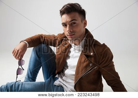 selaxed fahion man lying down on grey studio background